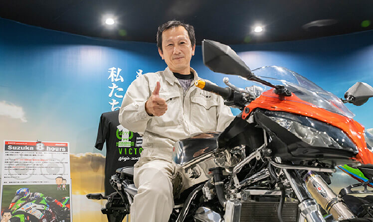 バイクにまたがっている GT 製造部長代理